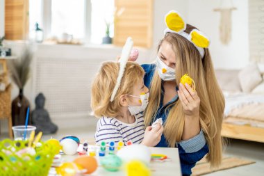 Mutlu anne ve oğul süslü tavşan maskesi takıyor kulaklık takıyor, Paskalya tatiline hazırlanıyor, aile karantina sırasında evde vakit geçiriyor.