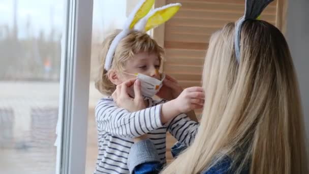 Família mascarada se divertindo durante o surto de coronavírus. Mãe e filho vestindo orelhas de coelho e trajes de coelho celebram a pandemia do coronavírus. Feliz feriado. — Vídeo de Stock
