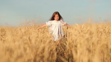 Uzun sarı saçlı güzel bir kız buğday tarlasında gülümsüyor. Güneşli bir günde arpa otlağında koşan hasır şapkalı şirin, mutlu bir bebek. Ağır çekimde kapat