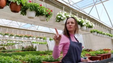 İnsanlar, bahçıvanlık, teknoloji ve meslek kavramı - mutlu kadın veya bahçıvan serada tablet bilgisayarı ve çiçekleri olan