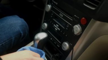 Bir el vites konsolunu arabanın içindeki mavi bir mikrofiber bezle siliyor..