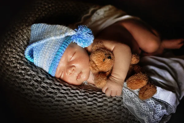 Recién nacido niño dormido envuelto en una manta de cerca, con un oso a mano — Foto de Stock