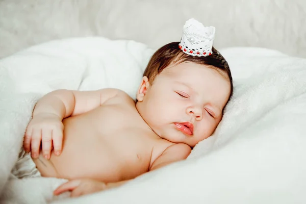 Newborn baby girl sleeps wrapped in white blanket. — Stock Photo, Image