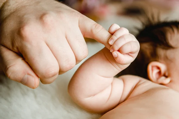 Newborn baby hand holding dads finger — Stock Photo, Image