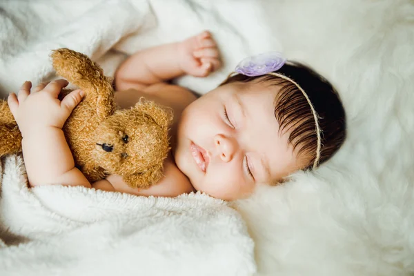 Newborn baby girl sleeps wrapped in white blanket. Stock Image