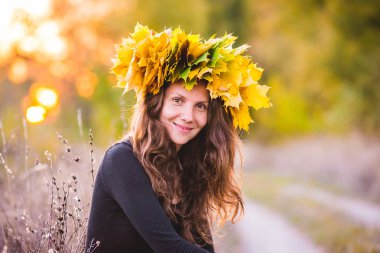 kafasına sarı yaprakların bir çelenk ile güzel kız