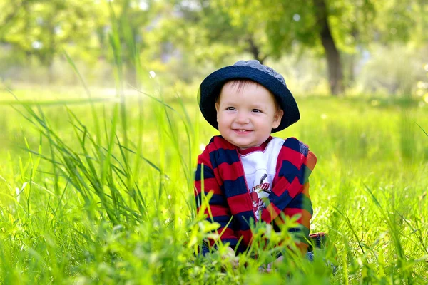 Kind zit in gras en glimlachen — Stockfoto