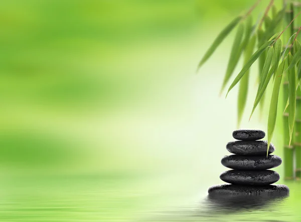 Fondo de spa con piedras de masaje apiladas y bambú — Foto de Stock