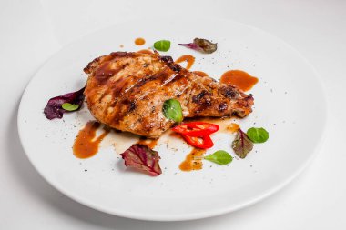 Fesleğenli beyaz tabakta kızarmış tavuk budu..