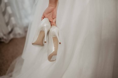 Gelin bir çift beyaz ayakkabı tutuyor. Bir çift nedime ayakkabısı..