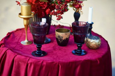 Şarap bardakları ve şamdanlar kırmızı masada..