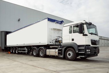 Büyük beyaz bir kamyon hangardan çıkıyor. vagon vagonu.