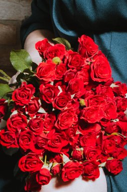 Kucağında bir buket taze gülle oturan zarif bir kadın. Görüntü hassasiyeti, kadınlığı ve kutlama duygusunu yansıtıyor. Aşk, güzellik, tatiller ve romantik anlar için mükemmel..