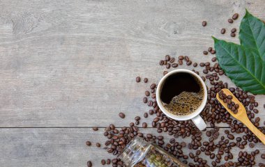 Ahşap zemin üzerinde bir fincan kahve ve fasulye. en üstteki görünüm