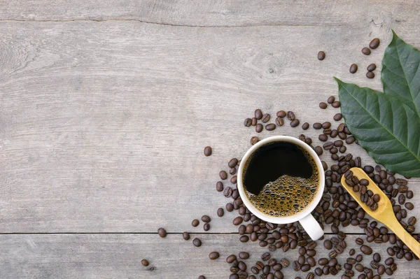 Ahşap zemin üzerinde bir fincan kahve ve fasulye. en üstteki görünüm