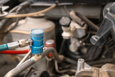 Arkaplanda hafif odaklı ve ışıktan oluşan tamir atölyesinde araba kliması tamir ediliyor.