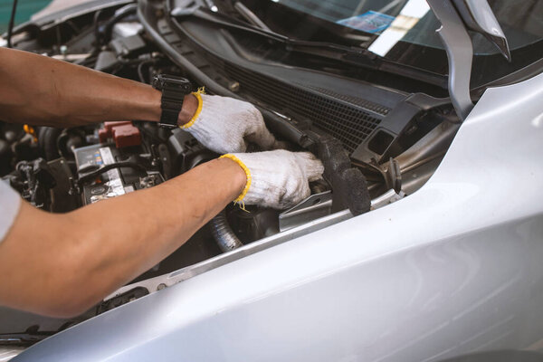 mechanic is checking the car in automobile repair service center with soft-focus and over light in the background