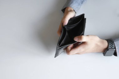 Yakın plan boş cüzdan (para yok) yumuşak odaklı bir adamın ellerinde ve arka planda ışık üzerinde