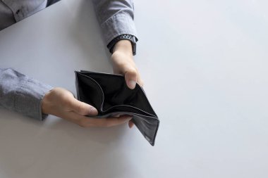 Yakın plan boş cüzdan (para yok) yumuşak odaklı bir adamın ellerinde ve arka planda ışık üzerinde