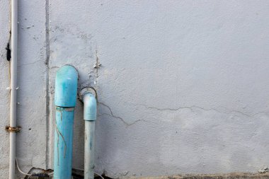 Beton duvar arka planında su tedarik sisteminin eski mavi PVC borusu