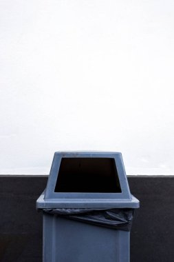 Beyaz çimento arka planında kapalı gri çöp kutusu