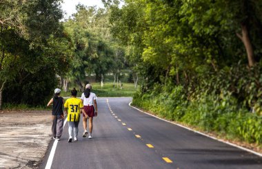 Parkta egzersiz yapan bir grup genç kadın, arka planda hafif odaklı ve ışığın üzerinde.