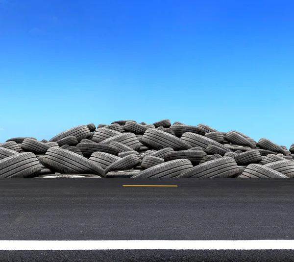 pile of used rubber tires on road with over light in blue sky background