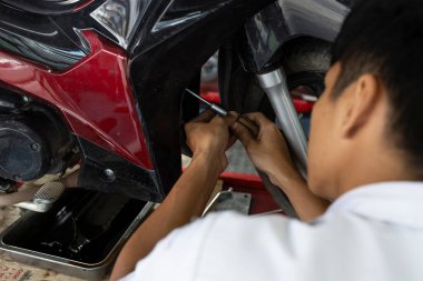 Aracın motor parçaları üzerinde çalışmak için elektrikli bir alet kullanan bir tamircinin yakın çekimi. Profesyonel tamir hizmeti, bakım ve otomotiv teknik uzmanlığı kavramı