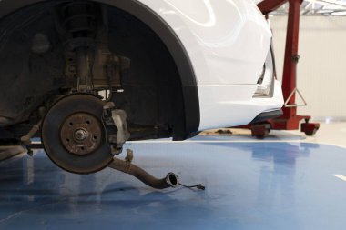 Tekerleği sökülmüş, fren sistemini gösteren bir araba şasisi. Otomotiv bakım ve onarım hizmeti kavramı