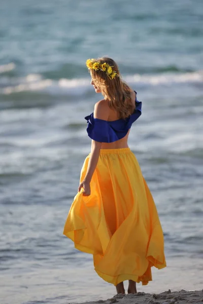 海の岸に黄色のスカートの若いブロンドの女の子 — ストック写真