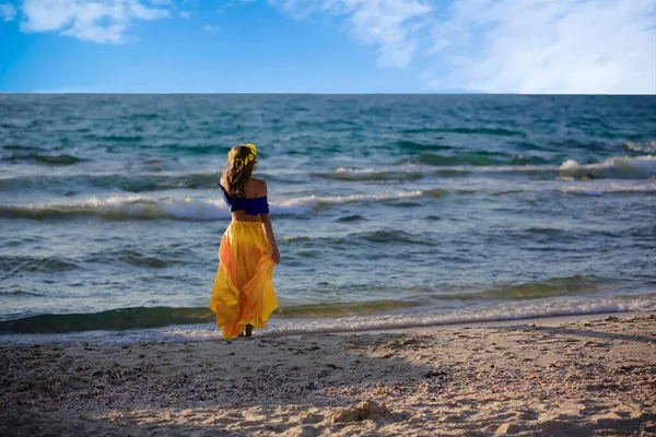 海の岸に黄色のスカートの若いブロンドの女の子 — ストック写真