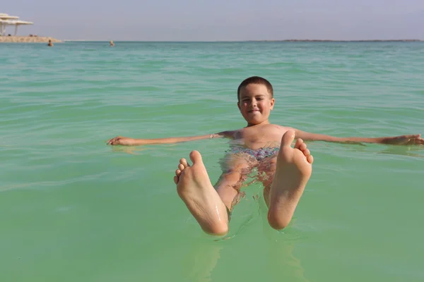 Junge treibt auf dem toten Meer Stockbild