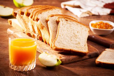 Kahvaltı için reçelli ekmek dilimleri ve meyve suyu.