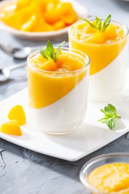 Bir bardak ev yapımı panna cotta ve mango sosu.