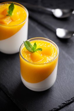 Bir bardak ev yapımı panna cotta ve mango sosu.