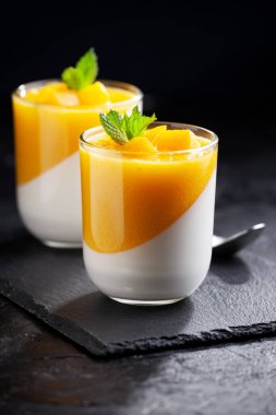 Bir bardak ev yapımı panna cotta ve mango sosu.