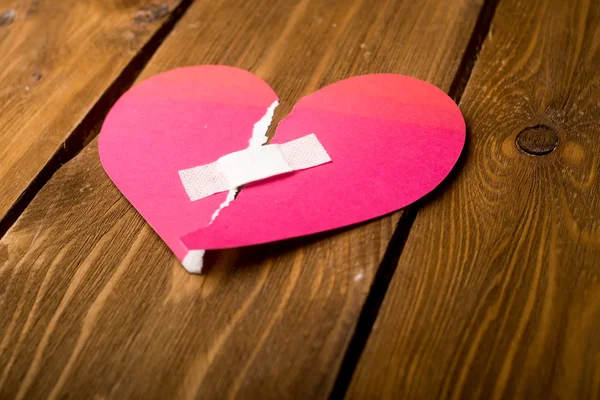 Close up of a plaster and paper broken heart on wooden backgroun — Stock Photo, Image