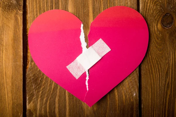 Close up of a plaster and paper broken heart on wooden backgroun — Stock Photo, Image