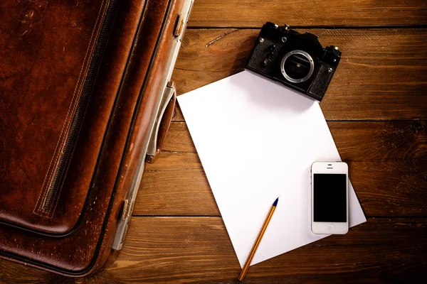 Kufr a starý fotoaparát, tablet, telefon a šálek kávy. — Stock fotografie