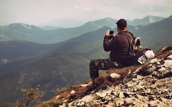 Viajante com binóculos sentado no topo de uma montanha — Fotografia de Stock