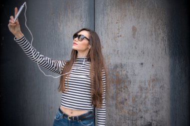 Metal paslı duvara karşı uzun saçlı esmer alarak selfie
