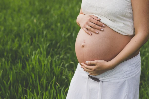 Primer plano de la mujer embarazada abrazando su vientre — Foto de Stock