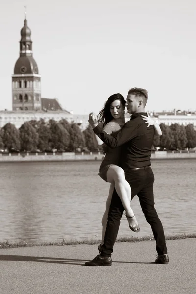 Young couple dancing tango against the old city background. Travel and lifestyle concepts. Black and white photo, portrait capture.