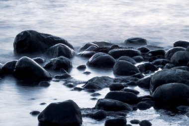 Uzun süre deniz ve kayalara maruz kalmış. Dalgalı denizden çıkan kayalar. Sakin sahne.