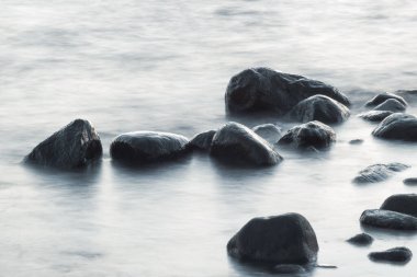 Uzun süre deniz ve kayalara maruz kalmış. Dalgalı denizden çıkan kayalar. Sakin sahne.