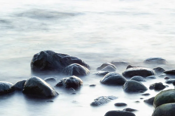 海と岩の長い露出 波が滑らかな海から突き出た岩 静物画 ストック画像