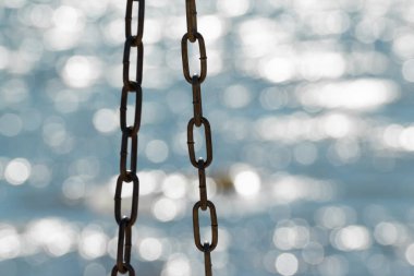Parlak suda izole edilmiş bir salıncaktan çıkan metal zincir. Güzel odaklanmış deniz arkaplanı