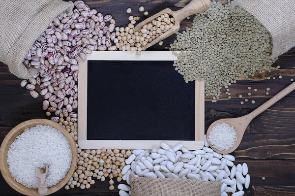 Diferentes cereales en bolsas textiles sobre mesa de madera —  Fotos de Stock