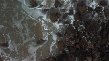 Deniz dalgalarının kayalara çarpma görüntüsü.