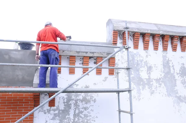 Trabalhador da construção civil rebocando uma parede velha — Fotografia de Stock